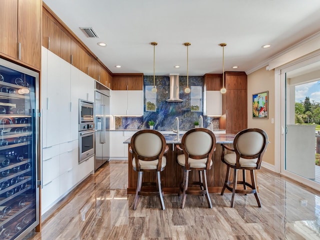 8 Sunset Bay Dr, Belleair, FL 33756 - kitchen featuring built in appliances, beverage cooler, wall chimney range hood, a kitchen island with sink, and tasteful backsplash