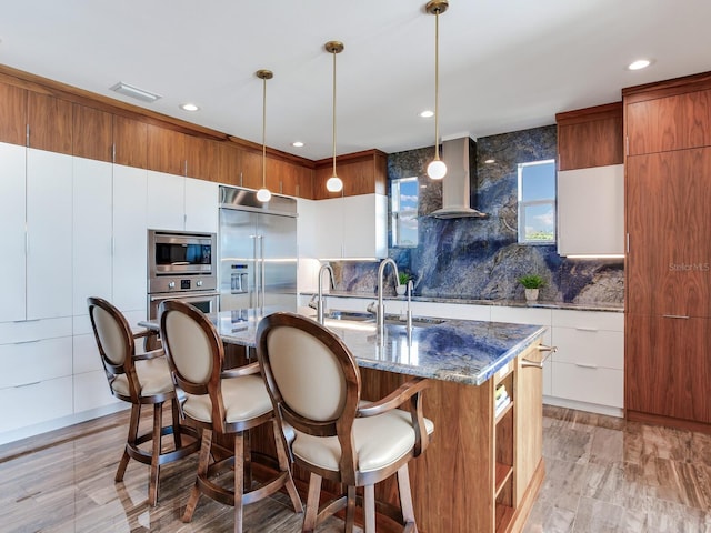 8 Sunset Bay Dr, Belleair, FL 33756 - kitchen featuring island exhaust hood, built in appliances, a kitchen island with sink, tasteful backsplash, and a breakfast bar area