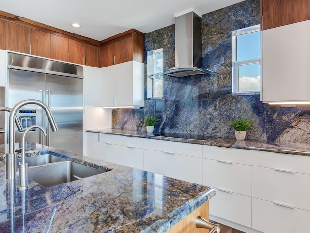 8 Sunset Bay Dr, Belleair, FL 33756 - kitchen featuring wall chimney range hood, built in fridge, decorative backsplash, dark stone counters, and recessed lighting