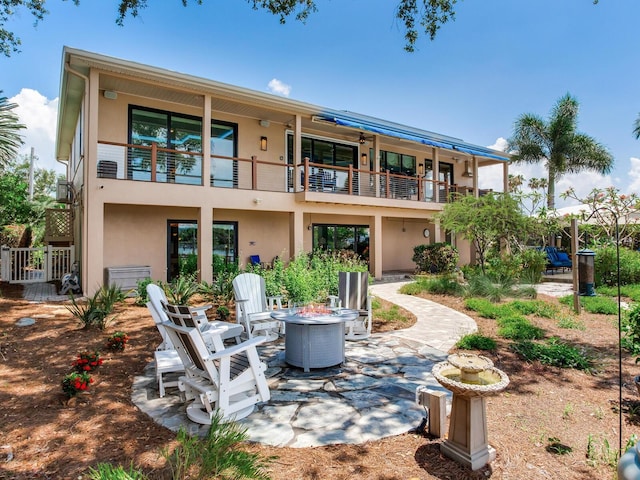 8 Sunset Bay Dr, Belleair, FL 33756 - back of property with a balcony, a fire pit, stucco siding, and a patio
