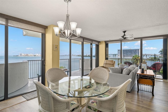 80 Rogers St Unit 3A, Clearwater, FL 33756 - dining area with a water view, expansive windows, a chandelier, ceiling fan, and wood finished floors