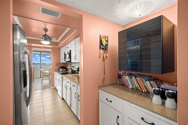 80 Rogers St Unit 3A, Clearwater, FL 33756 - kitchen with appliances with stainless steel finishes, white cabinetry, light tile patterned floors, backsplash, and a textured ceiling