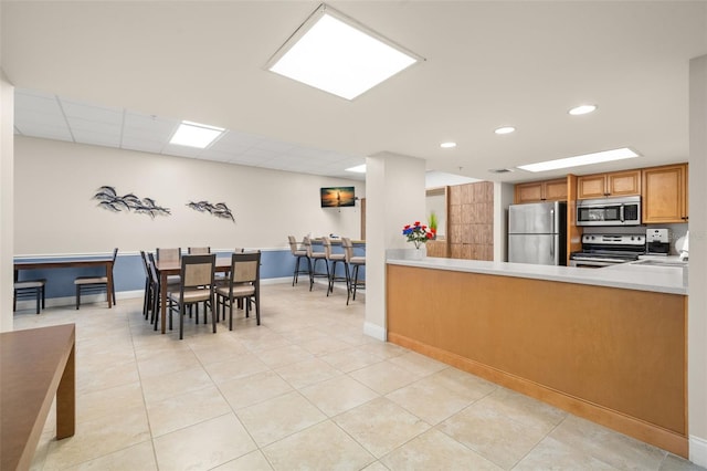 80 Rogers St Unit 3A, Clearwater, FL 33756 - kitchen with stainless steel appliances, light countertops, light tile patterned flooring, recessed lighting, and brown cabinetry