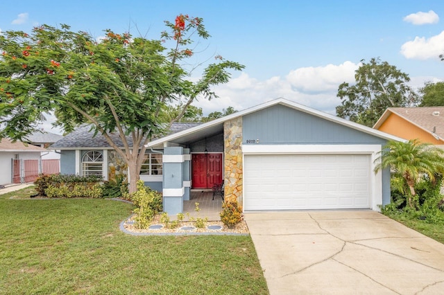 8629 Wolf Den Trl, Port Richey, FL 34668 - view of front facade with a garage, stone siding, a front lawn, and driveway