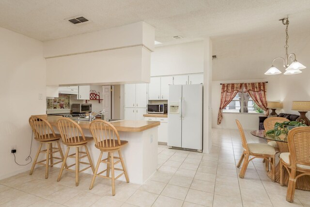 8629 Wolf Den Trl, Port Richey, FL 34668 - kitchen with white fridge with ice dispenser, stainless steel microwave, a peninsula, a chandelier, and a kitchen breakfast bar
