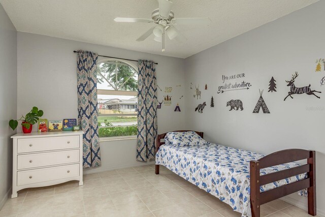 8629 Wolf Den Trl, Port Richey, FL 34668 - bedroom with a ceiling fan, light tile patterned floors, and a textured ceiling