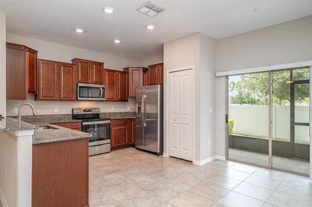 9741 Mulberry Marsh Ln, Sun City Center, FL 33573 - kitchen featuring stainless steel appliances, light stone counters, recessed lighting, brown cabinetry, and a peninsula