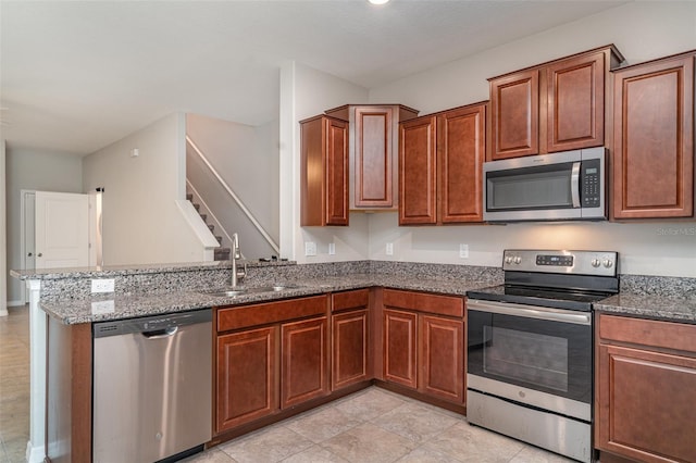 9741 Mulberry Marsh Ln, Sun City Center, FL 33573 - kitchen featuring appliances with stainless steel finishes, a peninsula, dark stone countertops, brown cabinets, and light tile patterned floors