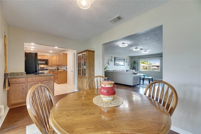 1502 Fort Duquesna Dr, Sun City Center, FL 33573 - dining room featuring a textured ceiling and light wood-style floors