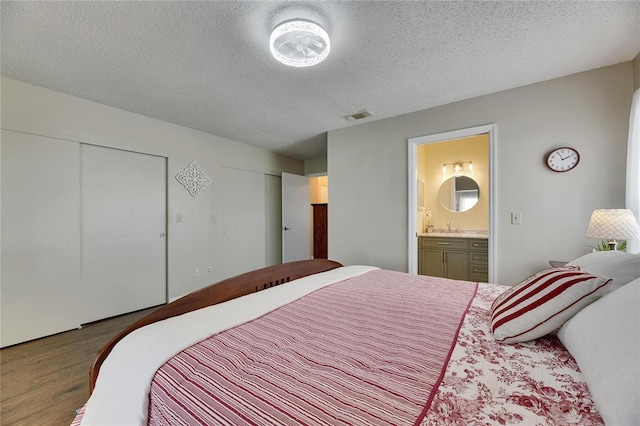 1502 Fort Duquesna Dr, Sun City Center, FL 33573 - bedroom featuring wood finished floors, two closets, a textured ceiling, and ensuite bathroom