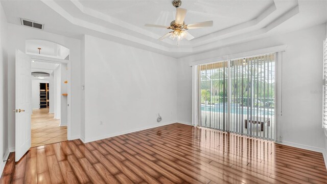 2202 Hickory Ridge Dr, Valrico, FL 33596 - empty room with a raised ceiling, arched walkways, a ceiling fan, and wood finished floors
