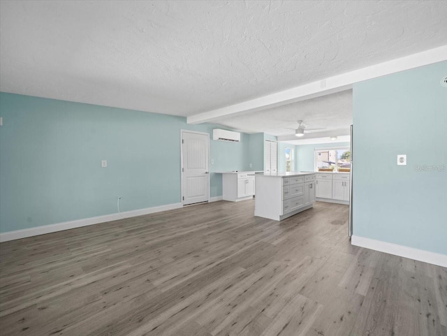 13316 Carol Dr, Hudson, FL 34667 - unfurnished living room with an AC wall unit, a textured ceiling, light wood-style flooring, beamed ceiling, and ceiling fan