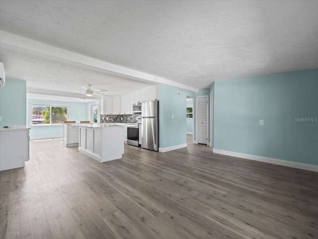 13316 Carol Dr, Hudson, FL 34667 - unfurnished living room featuring wood finished floors, a textured ceiling, a ceiling fan, and a wall mounted AC