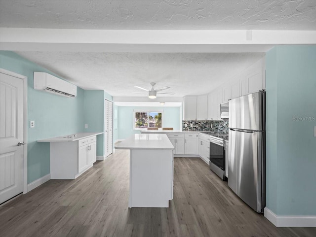 13316 Carol Dr, Hudson, FL 34667 - kitchen with appliances with stainless steel finishes, an AC wall unit, white cabinets, wood finished floors, and a textured ceiling