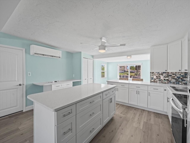 13316 Carol Dr, Hudson, FL 34667 - kitchen featuring a wall unit AC, stainless steel electric range oven, light wood-type flooring, light countertops, and a textured ceiling