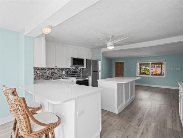 13316 Carol Dr, Hudson, FL 34667 - kitchen featuring stainless steel appliances, a breakfast bar area, tasteful backsplash, a textured ceiling, and light wood finished floors