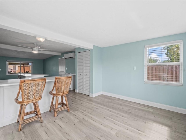13316 Carol Dr, Hudson, FL 34667 - kitchen featuring light wood-type flooring, a wall mounted air conditioner, ceiling fan, and light countertops