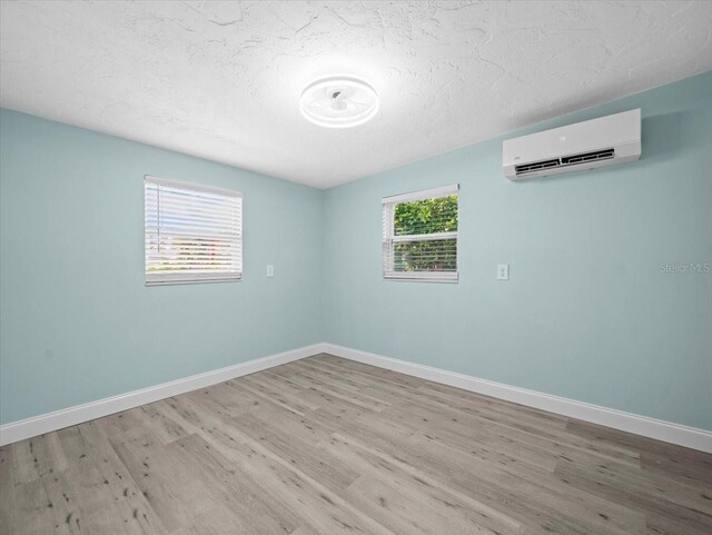 13316 Carol Dr, Hudson, FL 34667 - spare room with a wall mounted air conditioner, wood finished floors, and a textured ceiling
