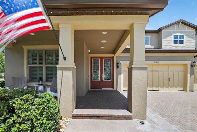 10313 Scarlet Chase Dr, Riverview, FL 33569 - property entrance with stucco siding, a garage, decorative driveway, and a porch