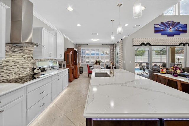10313 Scarlet Chase Dr, Riverview, FL 33569 - kitchen with wall chimney range hood, black electric cooktop, a kitchen island with sink, decorative backsplash, and crown molding