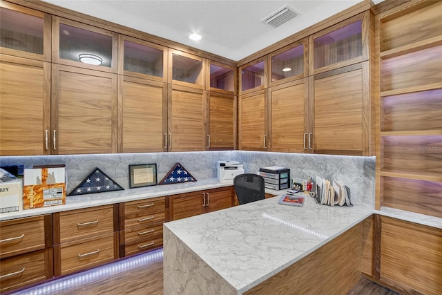 10313 Scarlet Chase Dr, Riverview, FL 33569 - kitchen featuring brown cabinetry, tasteful backsplash, a peninsula, glass insert cabinets, and light stone countertops