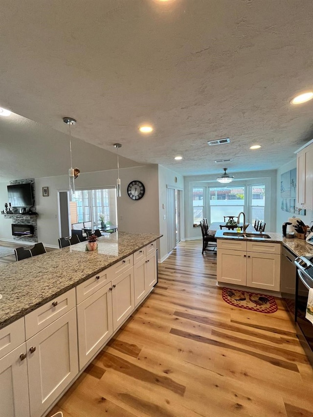 8616 Pinafore Dr, New Port Richey, FL 34653 - kitchen featuring light wood-type flooring, a peninsula, white cabinets, plenty of natural light, and recessed lighting