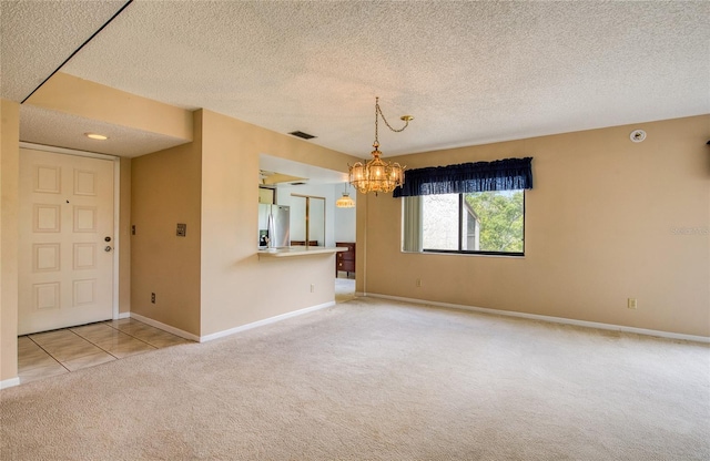 700 Starkey Rd Unit 1145, Largo, FL 33771 - spare room featuring light carpet, a chandelier, a textured ceiling, and light tile patterned floors