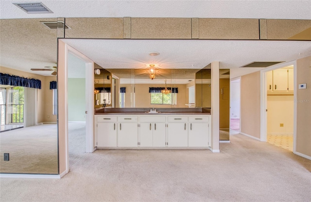 700 Starkey Rd Unit 1145, Largo, FL 33771 - kitchen featuring light colored carpet, a textured ceiling, plenty of natural light, white cabinets, and dark countertops