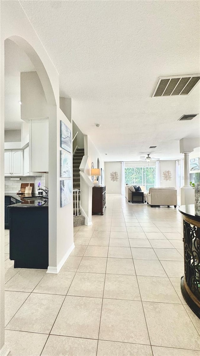 27312 Edenfield Dr, Wesley Chapel, FL 33544 - corridor with light tile patterned floors, a textured ceiling, arched walkways, and stairway