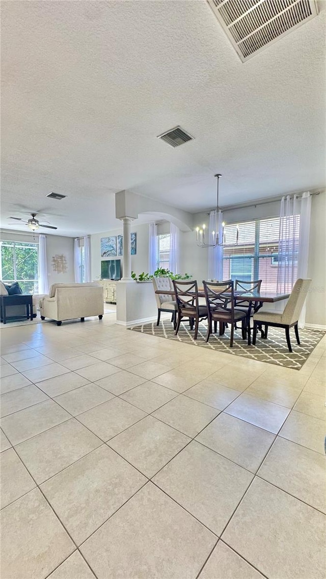 27312 Edenfield Dr, Wesley Chapel, FL 33544 - dining area with light tile patterned flooring, healthy amount of natural light, a textured ceiling, a chandelier, and decorative columns