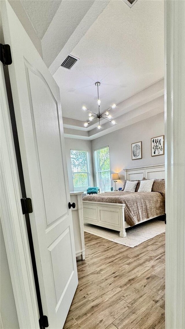 27312 Edenfield Dr, Wesley Chapel, FL 33544 - bedroom featuring light wood-style flooring, a textured ceiling, and a chandelier
