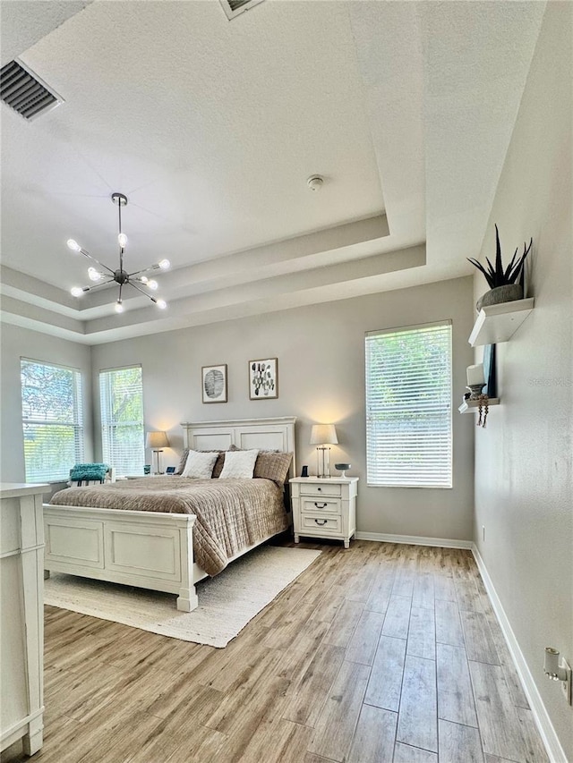 27312 Edenfield Dr, Wesley Chapel, FL 33544 - bedroom featuring a raised ceiling, light wood finished floors, a chandelier, and a textured ceiling