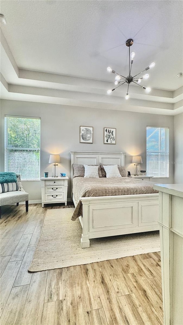 27312 Edenfield Dr, Wesley Chapel, FL 33544 - bedroom with a chandelier, a tray ceiling, light wood finished floors, and a textured ceiling