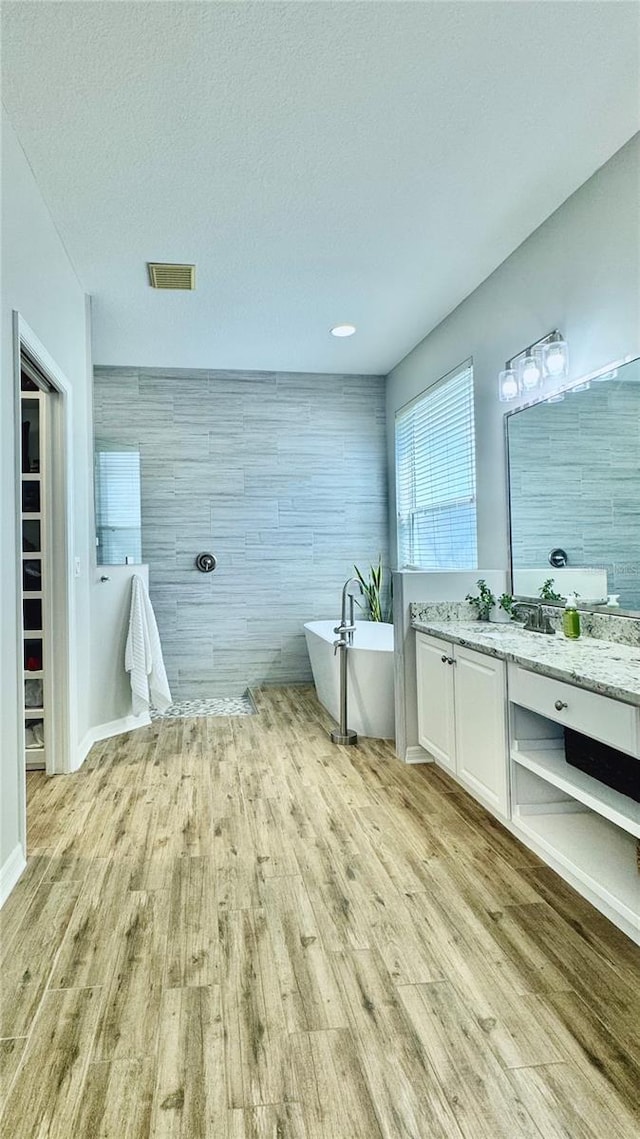 27312 Edenfield Dr, Wesley Chapel, FL 33544 - full bathroom with vanity, a soaking tub, wood finished floors, and a textured ceiling