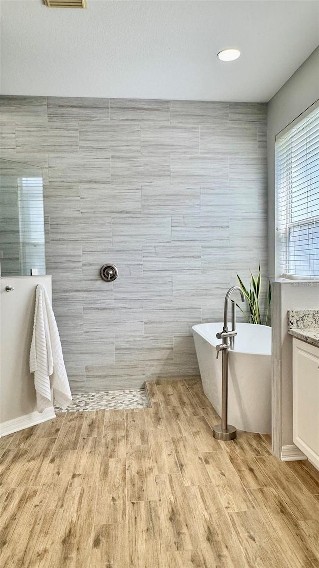 27312 Edenfield Dr, Wesley Chapel, FL 33544 - bathroom with vanity, a freestanding bath, wood finished floors, and tile walls