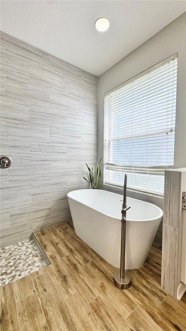 27312 Edenfield Dr, Wesley Chapel, FL 33544 - full bathroom featuring tile walls, a freestanding bath, and wood finished floors