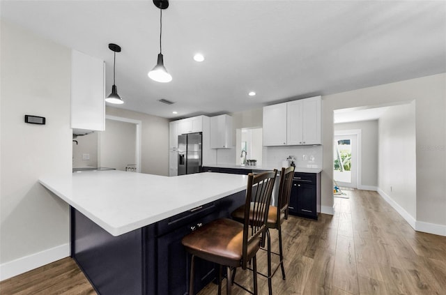 1800 Mapleleaf Blvd, Oldsmar, FL 34677 - kitchen featuring stainless steel refrigerator with ice dispenser, dark wood-style flooring, a breakfast bar area, white cabinetry, and a peninsula