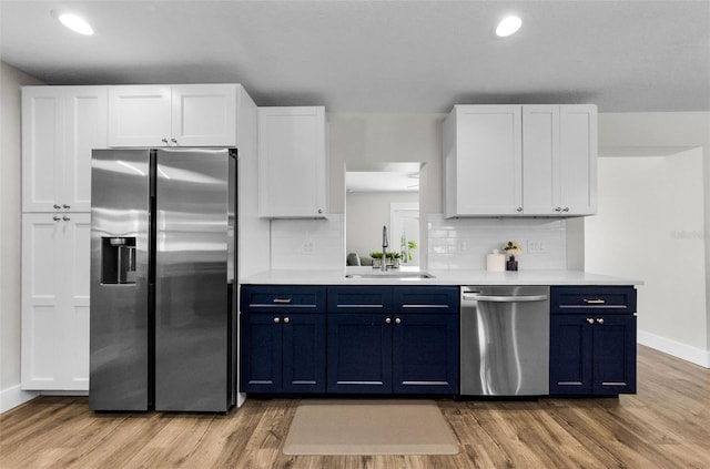1800 Mapleleaf Blvd, Oldsmar, FL 34677 - kitchen featuring stainless steel appliances, blue cabinets, light countertops, light wood finished floors, and backsplash