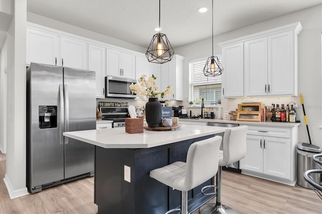 6352 Mooring Line Cir, Apollo Beach, FL 33572 - kitchen featuring stainless steel appliances, a center island, white cabinets, light wood finished floors, and recessed lighting
