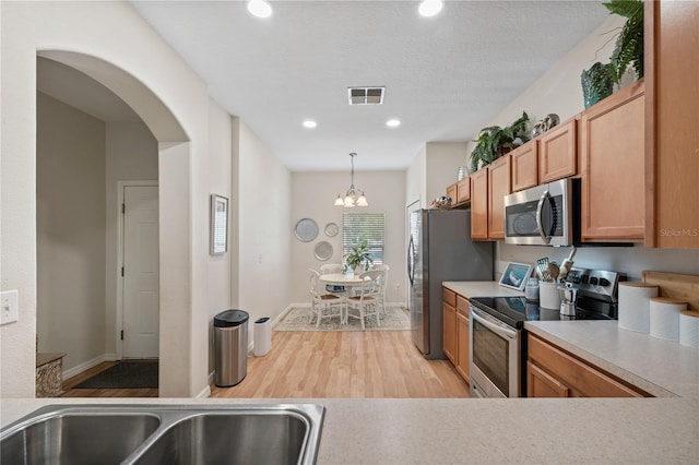 2349 Willimette Dr, Wesley Chapel, FL 33543 - kitchen featuring stainless steel appliances, light wood-style floors, light countertops, arched walkways, and recessed lighting