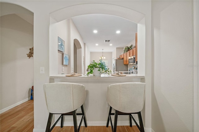 2349 Willimette Dr, Wesley Chapel, FL 33543 - kitchen with stainless steel appliances, a breakfast bar area, light wood-style floors, light countertops, and recessed lighting