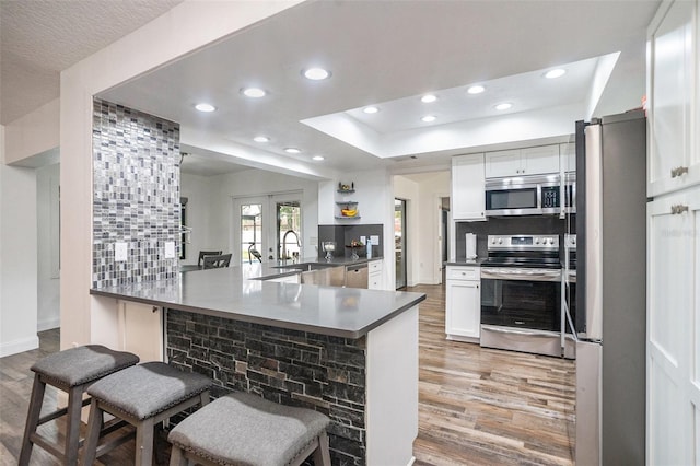 2701 Herndon St, Valrico, FL 33596 - kitchen featuring appliances with stainless steel finishes, light wood-style flooring, a breakfast bar, recessed lighting, and decorative backsplash