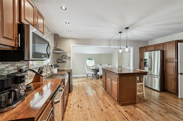 1722 Albemarle Rd, Clearwater, FL 33764 - kitchen with stainless steel appliances, wall chimney range hood, butcher block countertops, a kitchen bar, and light wood-style floors