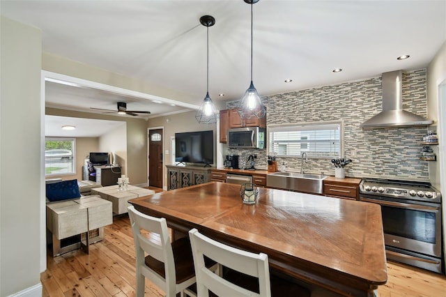1722 Albemarle Rd, Clearwater, FL 33764 - kitchen with appliances with stainless steel finishes, wall chimney range hood, tasteful backsplash, light wood-style floors, and open floor plan