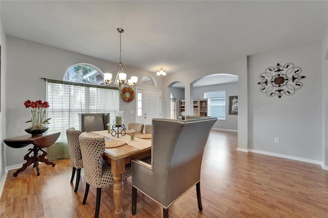 607 Tuscanny St, Brandon, FL 33511 - dining area with arched walkways, light wood-style flooring, and a chandelier