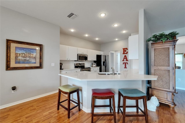 607 Tuscanny St, Brandon, FL 33511 - kitchen featuring stainless steel appliances, a breakfast bar area, light wood-style flooring, white cabinets, and a peninsula