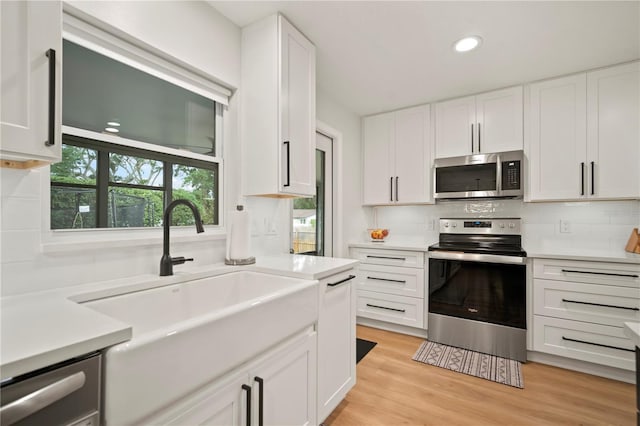 22238 River Rock Dr, Land O Lakes, FL 34639 - kitchen with stainless steel appliances, white cabinetry, light countertops, backsplash, and recessed lighting
