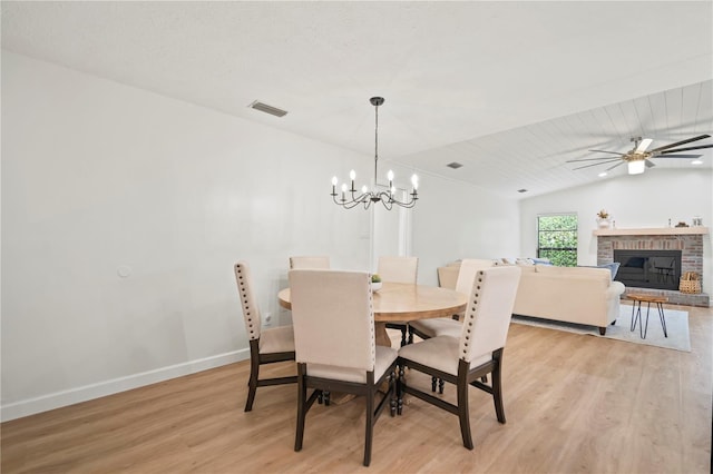 22238 River Rock Dr, Land O Lakes, FL 34639 - dining area with light wood-type flooring, a fireplace, a chandelier, ceiling fan, and vaulted ceiling