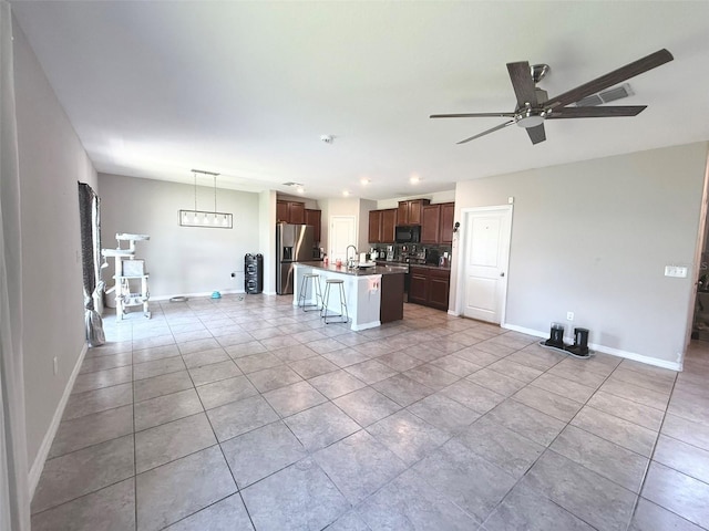 10221 Carloway Hills Dr, Wimauma, FL 33598 - kitchen featuring stainless steel refrigerator with ice dispenser, black microwave, ceiling fan, a center island with sink, and light tile patterned flooring
