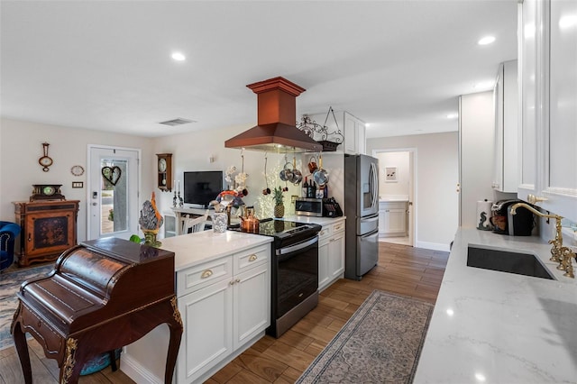 621 77th Ave, St Pete Beach, FL 33706 - kitchen with appliances with stainless steel finishes, island range hood, white cabinets, wood finished floors, and recessed lighting